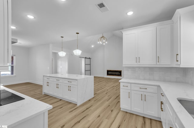 kitchen with a barn door, white cabinetry, and light hardwood / wood-style floors