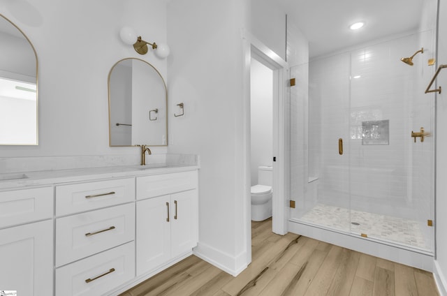 bathroom with hardwood / wood-style flooring, vanity, toilet, and walk in shower