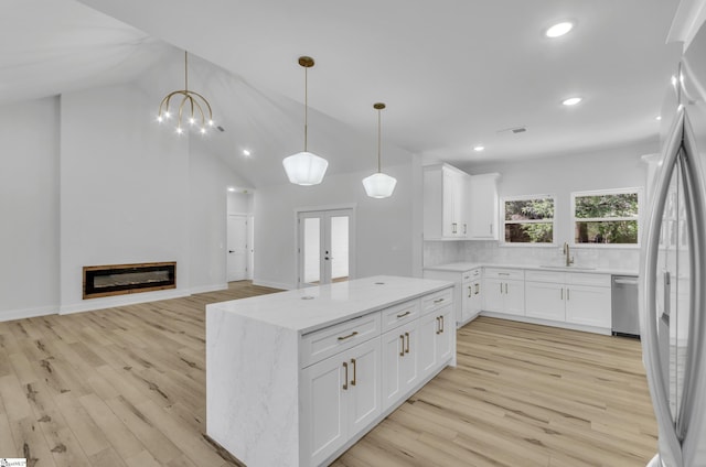 kitchen with white cabinetry, hanging light fixtures, and light hardwood / wood-style flooring