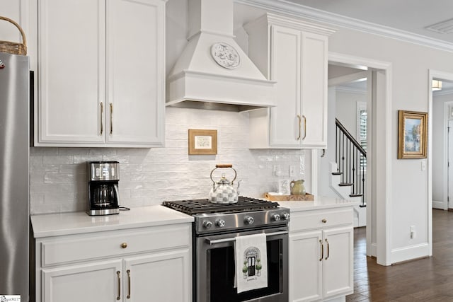 kitchen with appliances with stainless steel finishes, premium range hood, crown molding, white cabinets, and dark hardwood / wood-style floors