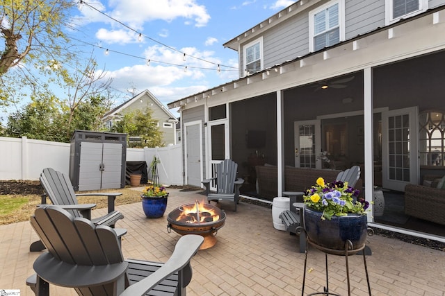 view of patio with a fire pit, a storage unit, and a sunroom