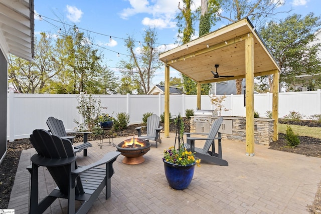 view of patio with a grill, ceiling fan, area for grilling, and a fire pit