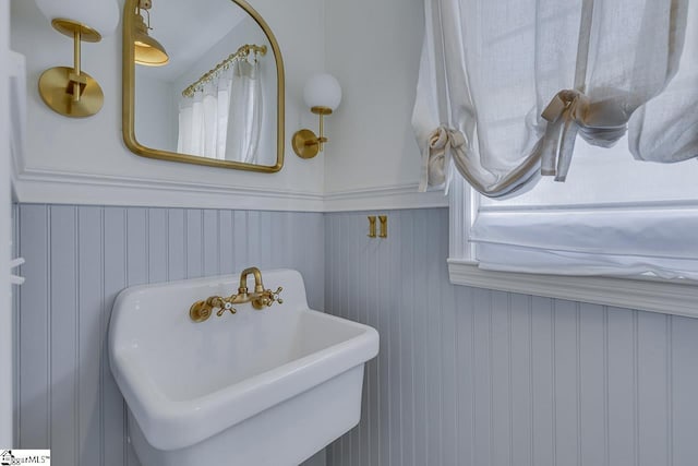 bathroom featuring wooden walls and sink