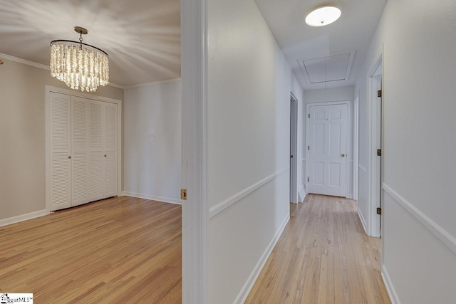 hall featuring crown molding, light hardwood / wood-style floors, and an inviting chandelier