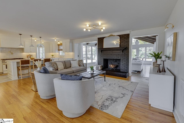 living room with a fireplace, plenty of natural light, and light wood-type flooring