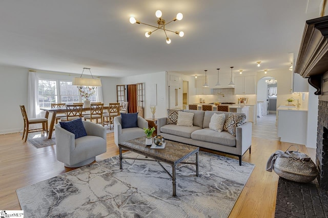 living room featuring a fireplace, light wood-type flooring, and an inviting chandelier