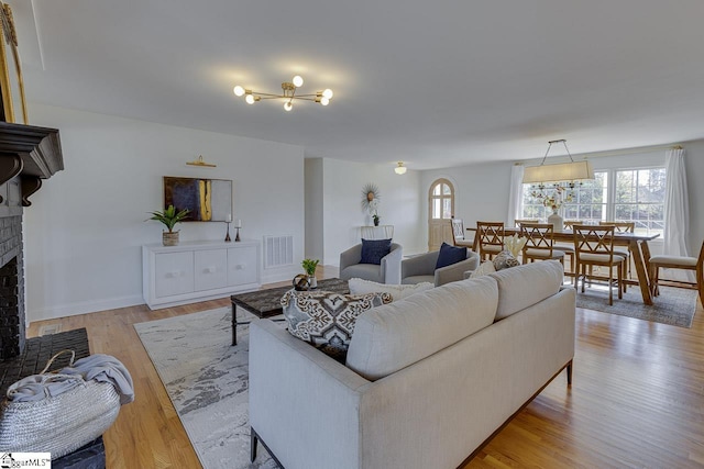 living room with light wood-type flooring and a brick fireplace