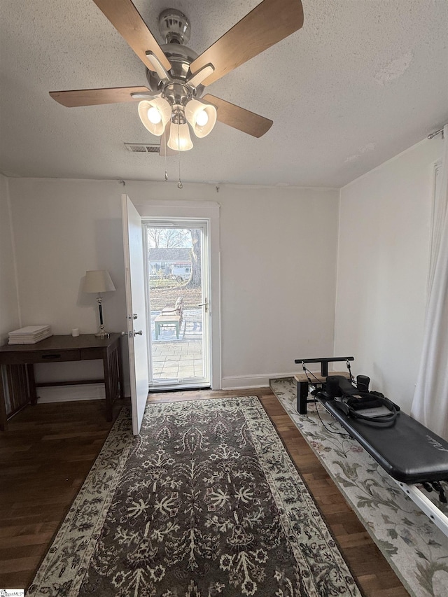 doorway featuring ceiling fan, dark hardwood / wood-style flooring, and a textured ceiling