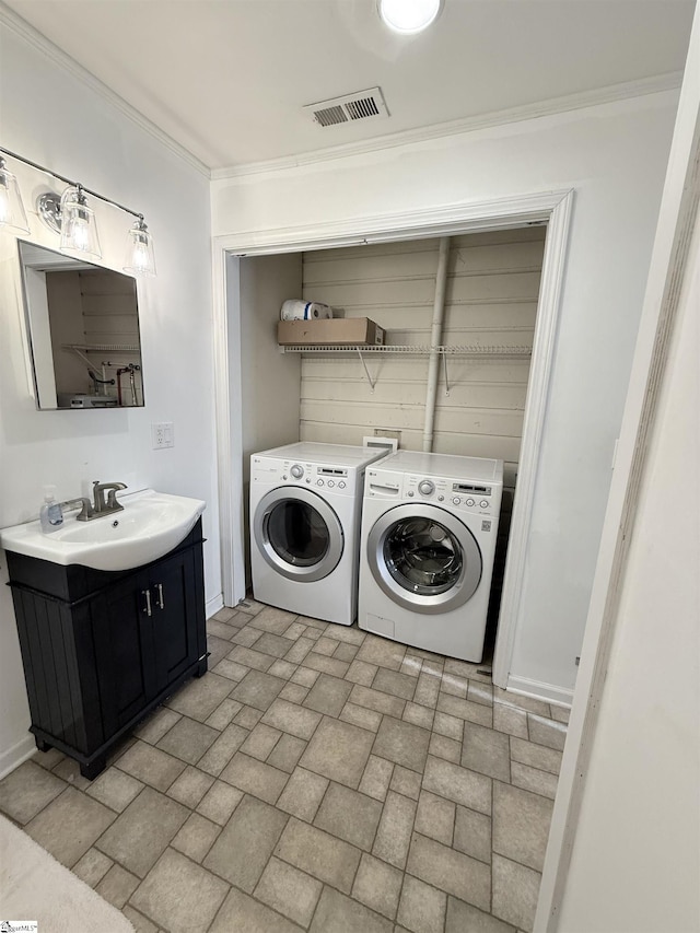 clothes washing area featuring washing machine and dryer, ornamental molding, and sink