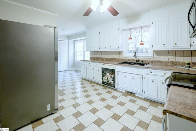 kitchen with hanging light fixtures, sink, black dishwasher, white cabinetry, and stainless steel refrigerator