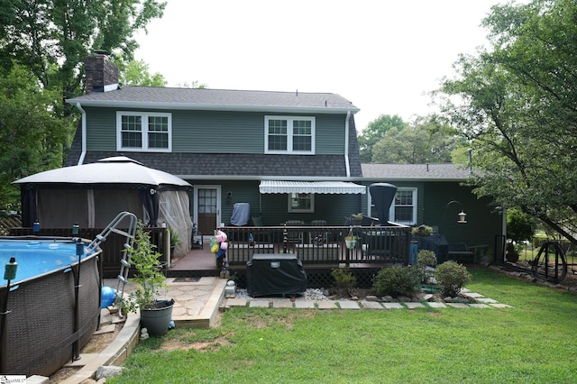 rear view of house with a gazebo, a swimming pool side deck, and a lawn