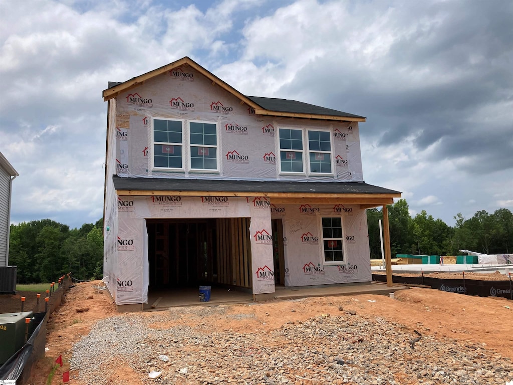 unfinished property featuring central AC unit and a garage