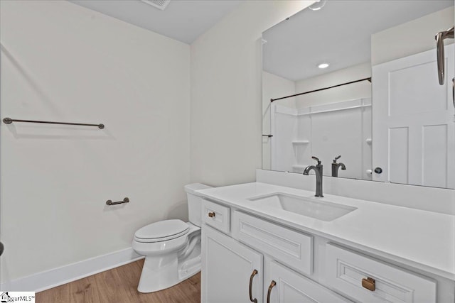 bathroom with a shower, hardwood / wood-style floors, vanity, and toilet