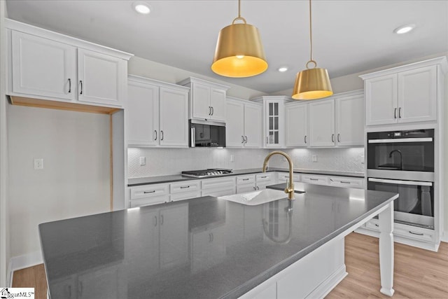 kitchen with white cabinets, decorative backsplash, stainless steel appliances, and sink