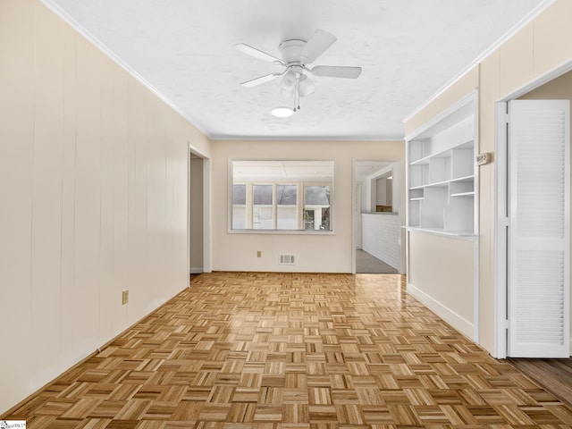 interior space with light parquet flooring, ceiling fan, and crown molding