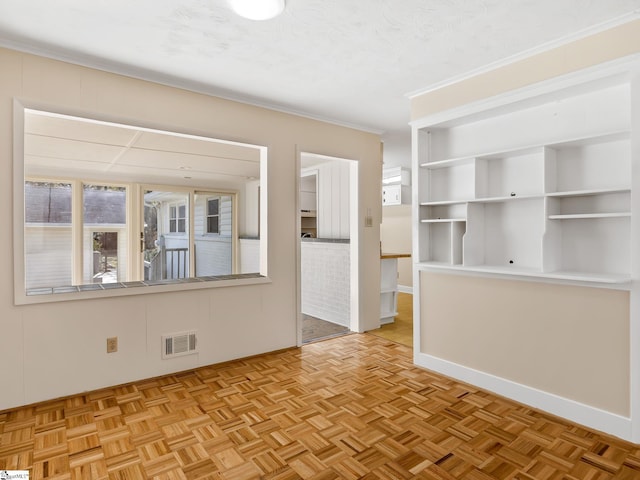 empty room featuring a textured ceiling, light parquet floors, and crown molding