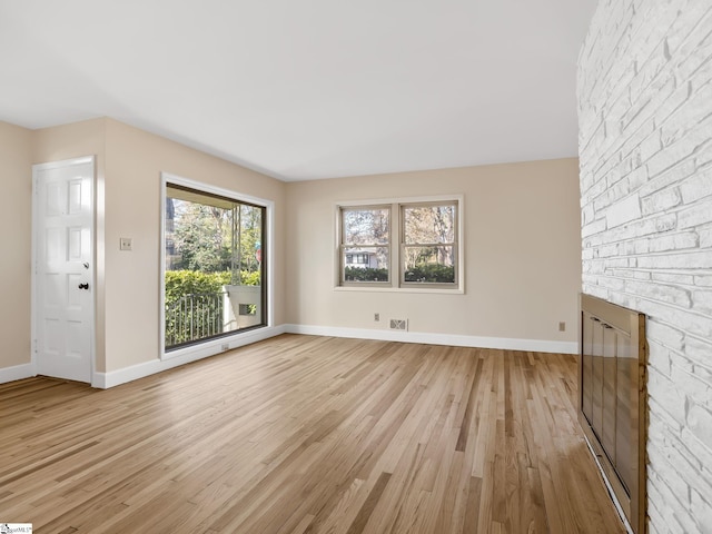 unfurnished living room featuring a stone fireplace and light wood-type flooring