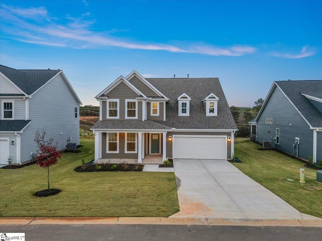 view of front of house with a porch, a garage, a front lawn, and central air condition unit