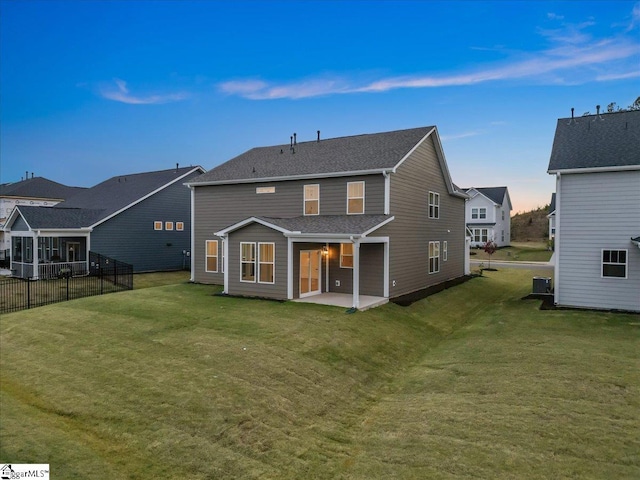 back house at dusk with a yard, a patio, and cooling unit