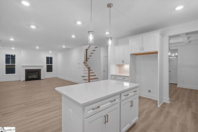 kitchen with white cabinets, light wood-type flooring, tasteful backsplash, decorative light fixtures, and a kitchen island