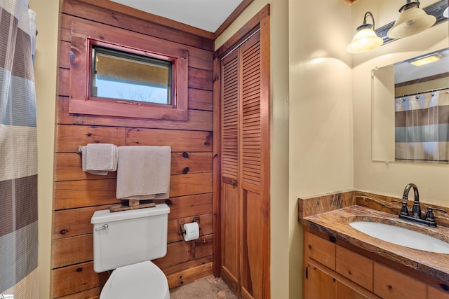 bathroom with vanity, toilet, and wooden walls