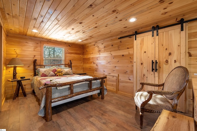 bedroom featuring hardwood / wood-style floors, a barn door, wooden walls, and wood ceiling