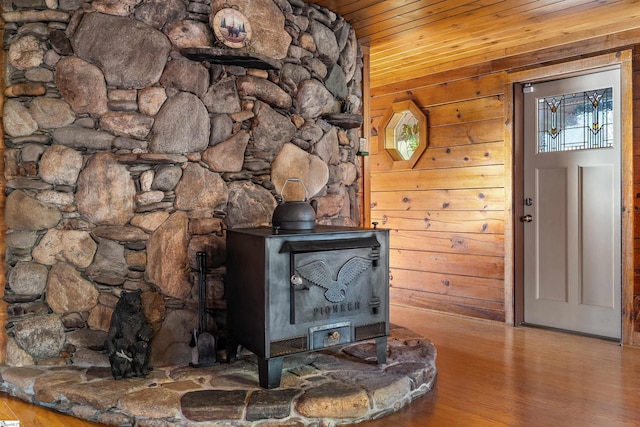 room details with wood-type flooring, wooden walls, a wood stove, and wooden ceiling