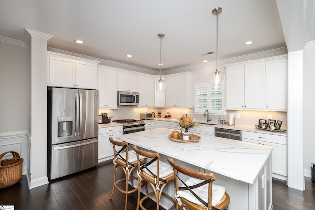 kitchen with a center island, dark wood-type flooring, stainless steel appliances, decorative light fixtures, and white cabinets