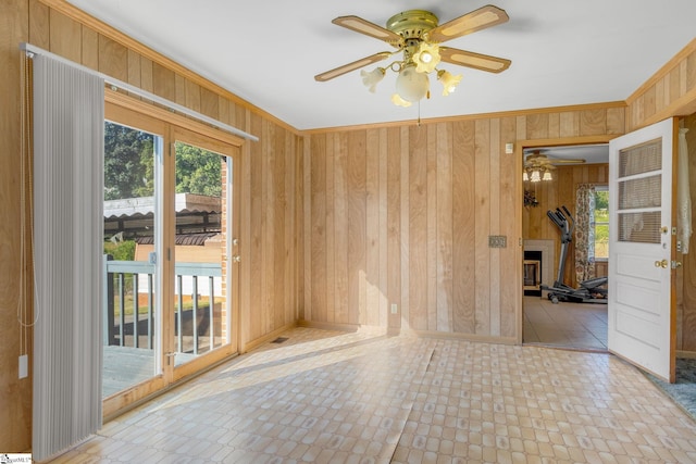 empty room with wooden walls, crown molding, and ceiling fan