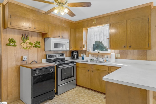 kitchen featuring ceiling fan, wooden walls, sink, black dishwasher, and stainless steel electric range oven