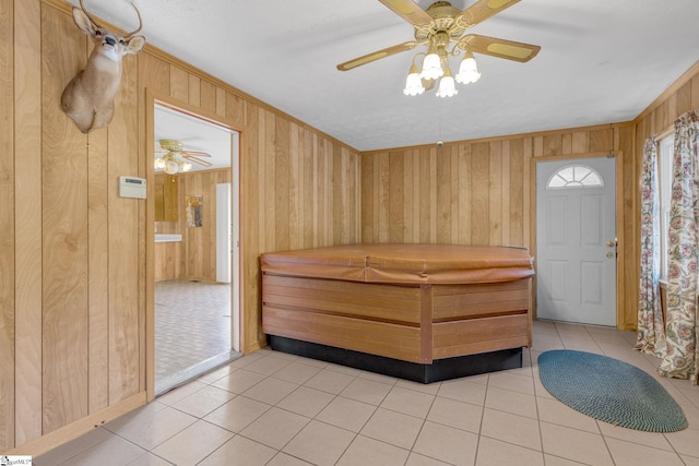 interior space with ceiling fan and wooden walls