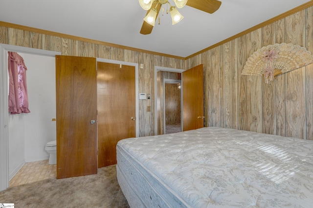 carpeted bedroom with a closet, ensuite bathroom, ceiling fan, and crown molding