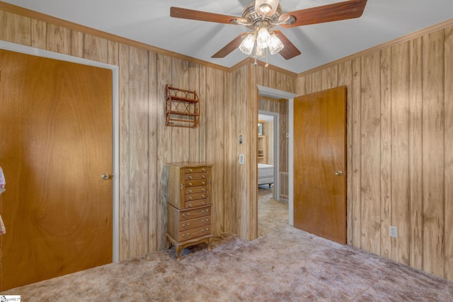 unfurnished bedroom featuring carpet flooring, ceiling fan, and wooden walls