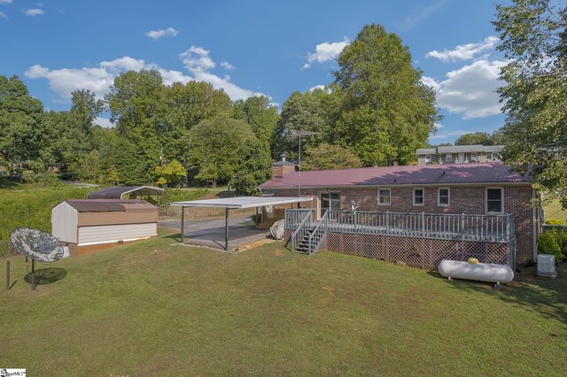 rear view of property featuring a yard, central AC, a carport, and a wooden deck