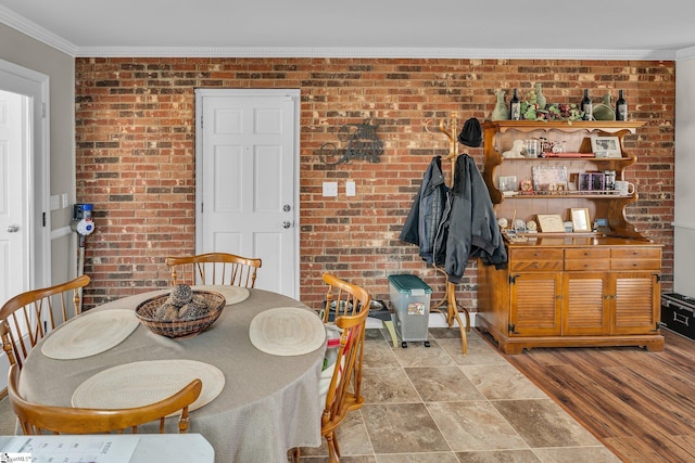 dining room with crown molding, brick wall, and light hardwood / wood-style floors