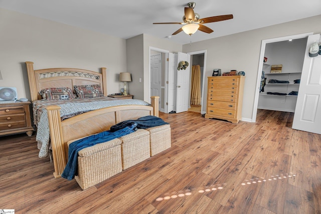 bedroom featuring a spacious closet, a closet, ceiling fan, and hardwood / wood-style flooring