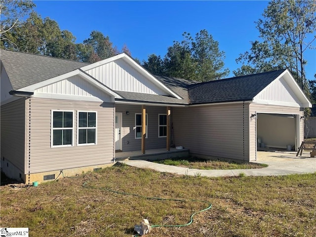 view of front of property with covered porch, a garage, and a front yard