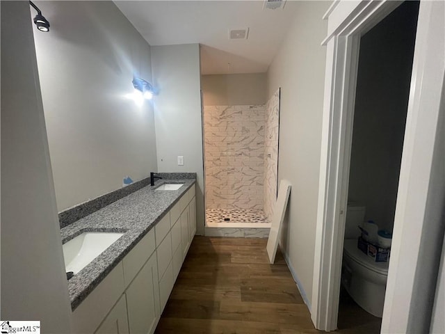 bathroom with hardwood / wood-style flooring, vanity, toilet, and a shower