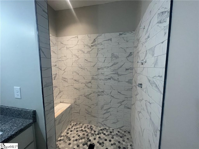 bathroom featuring tiled shower and vanity