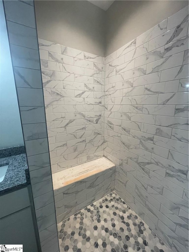 bathroom featuring a tile shower and vanity