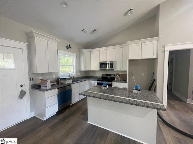 kitchen featuring appliances with stainless steel finishes, vaulted ceiling, sink, white cabinets, and a kitchen island