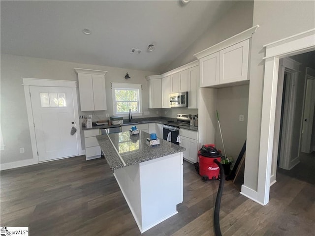 kitchen with white cabinetry, a kitchen island, lofted ceiling, and appliances with stainless steel finishes