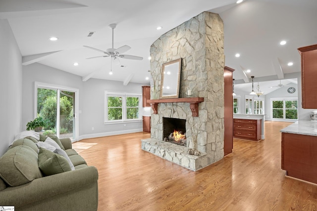 living room with ceiling fan, light hardwood / wood-style floors, a fireplace, and vaulted ceiling