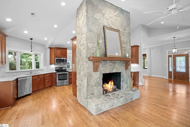 kitchen with a healthy amount of sunlight, a stone fireplace, appliances with stainless steel finishes, and light hardwood / wood-style flooring