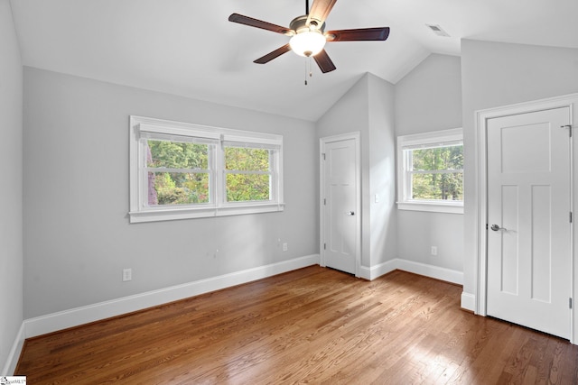 unfurnished bedroom featuring multiple windows, hardwood / wood-style flooring, vaulted ceiling, and ceiling fan