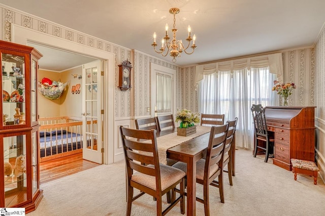 dining area with french doors, light wood-type flooring, crown molding, and a chandelier