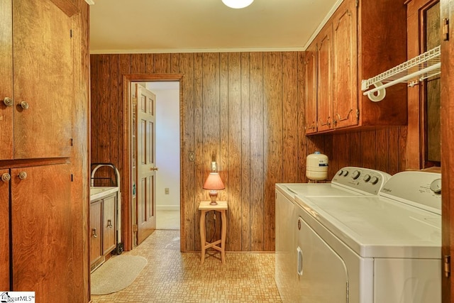 clothes washing area featuring cabinets, ornamental molding, wood walls, washing machine and clothes dryer, and light tile patterned flooring