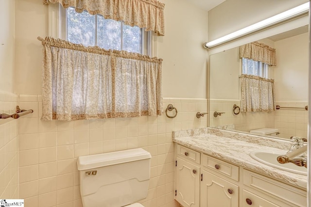 bathroom with vanity, toilet, and tile walls