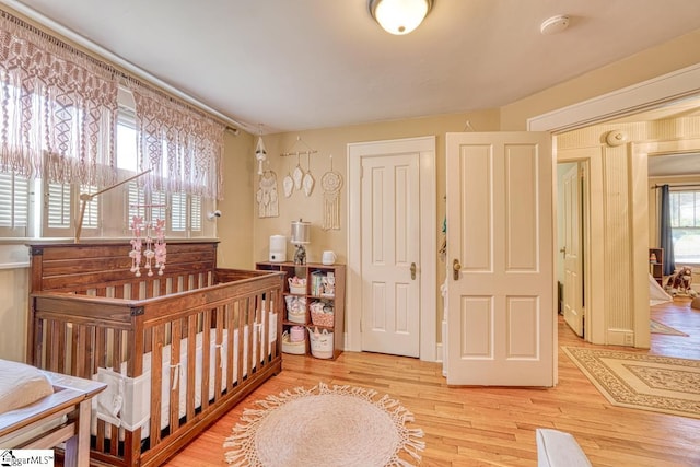 bedroom featuring wood-type flooring and a nursery area