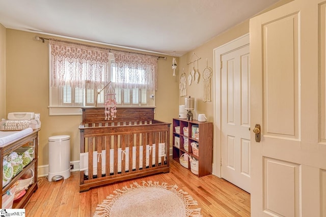 bedroom with light hardwood / wood-style flooring and a nursery area